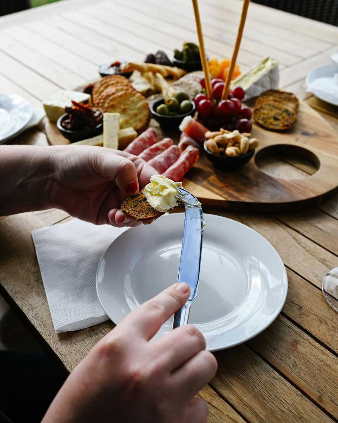 Hands assembling a cheese and antipasto platter on the deck