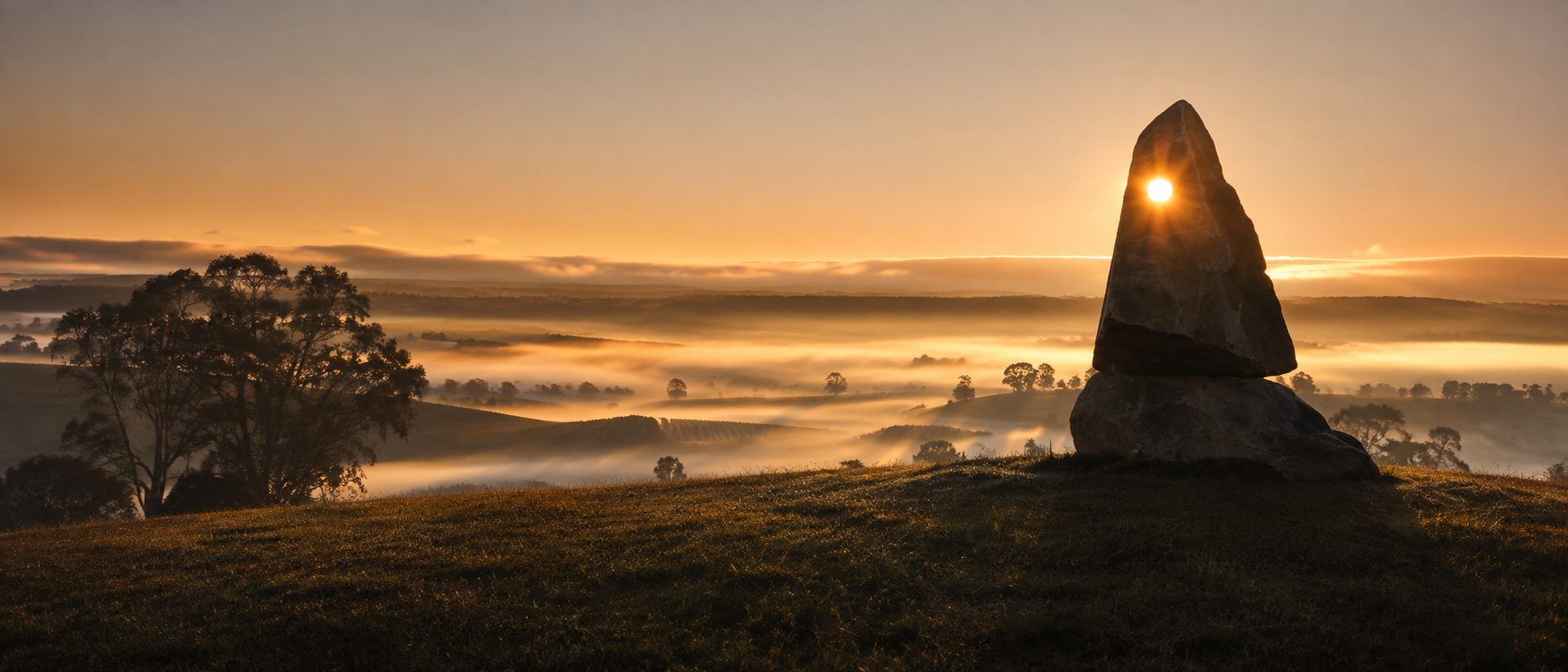 The Custodians of the Landscape sandstone sculptures at dawn, vineyard behind